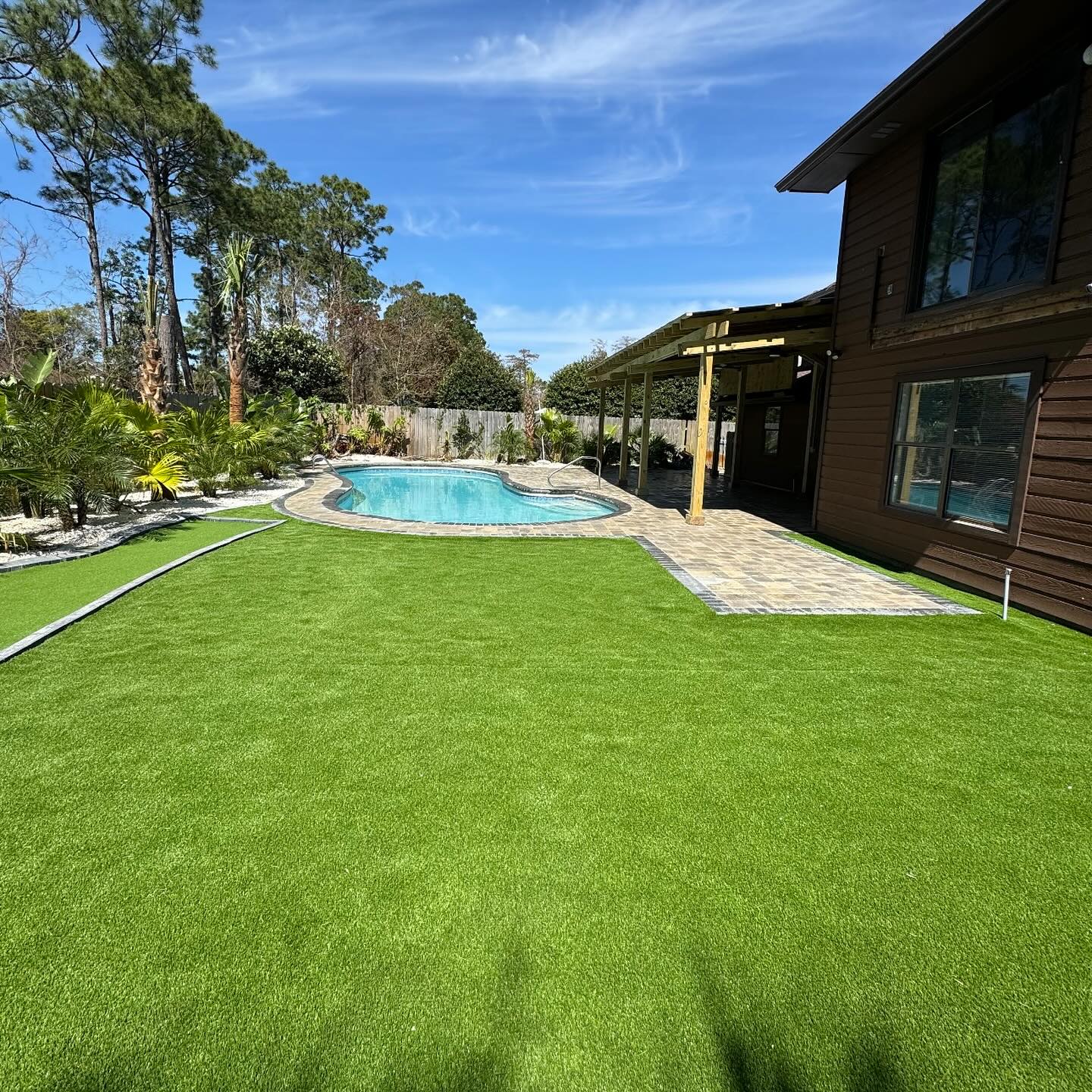 Backyard pool with fresh turf and palms in Panama City Beach